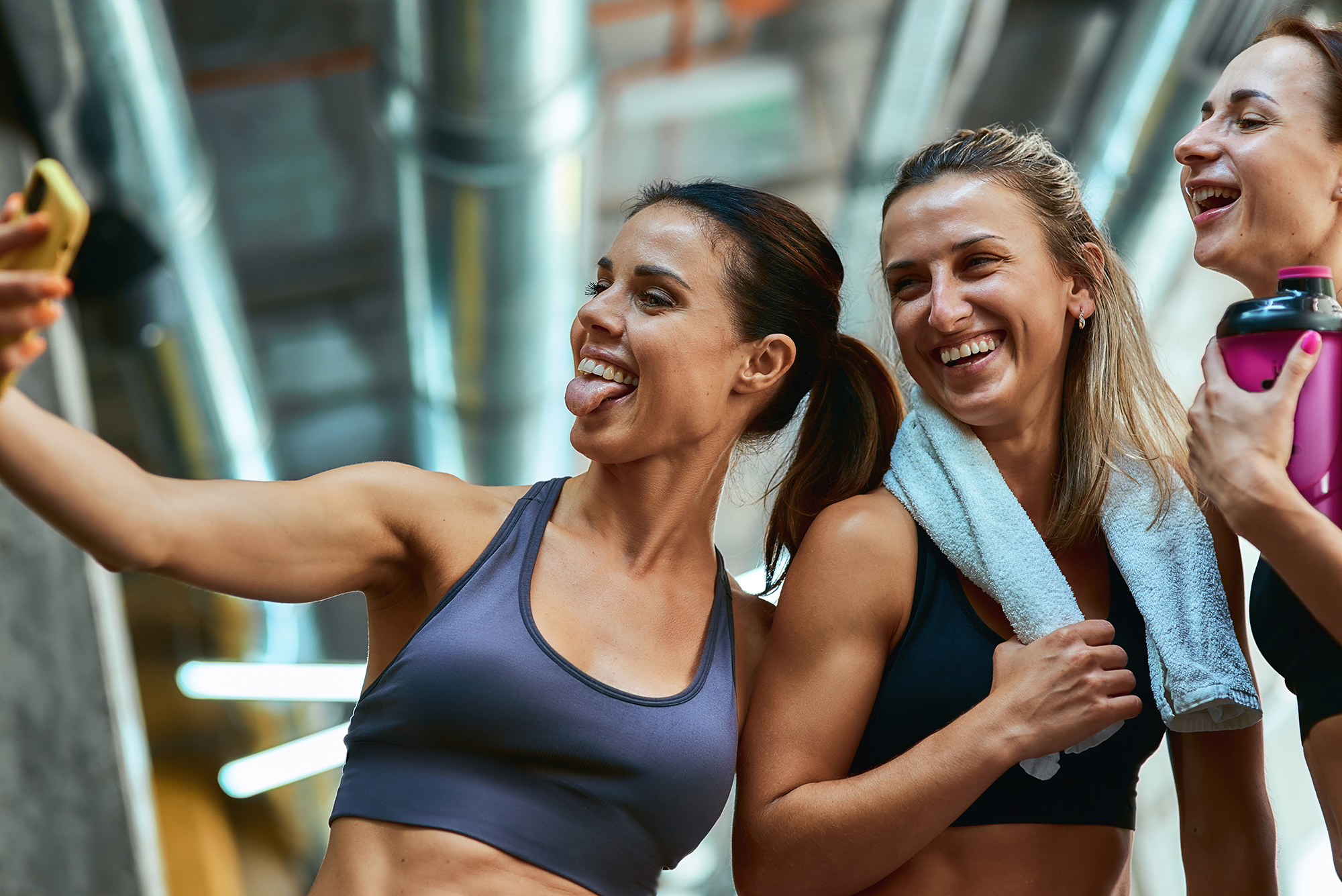 Having fun. Group of three young beautiful and joyful sportive women taking selfie on smartphone while resting after workout at gym - Legends Custom Lockers locker rooms